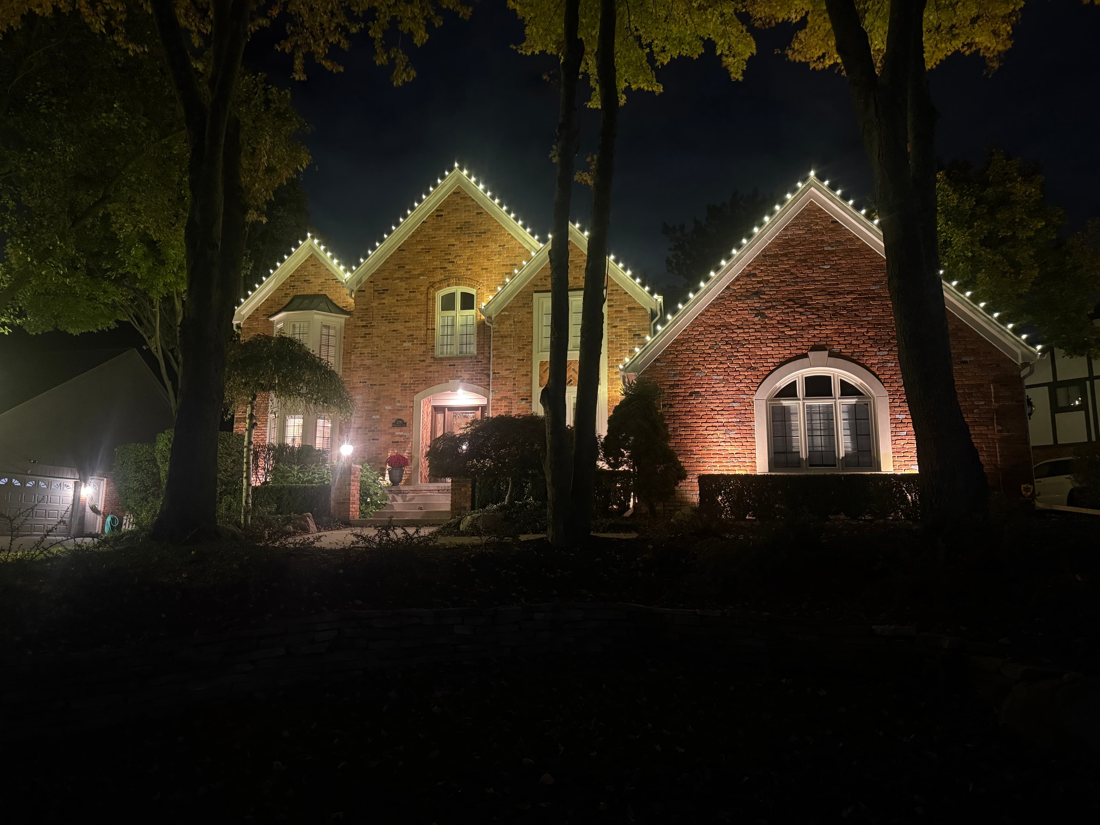 Neighborhood home glowing with Christmas lights at dusk